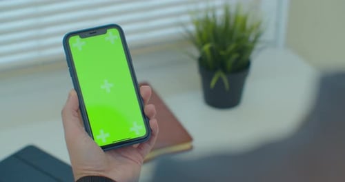 Man Using Vertical Smartphone with Green Screen. Close-up Shot of Man's Hands with Mobile Phone