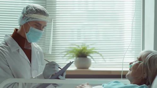 Doctor in Protective Uniform Visiting Elderly Woman in Hospital Ward