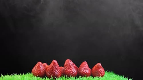 Pile of Red Strawberries on Green Grass with Black Background