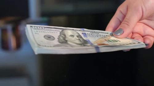 Stack of Money Being Passed Between Hands