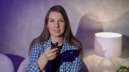 Woman Using Remote at Home in Dim Lighting