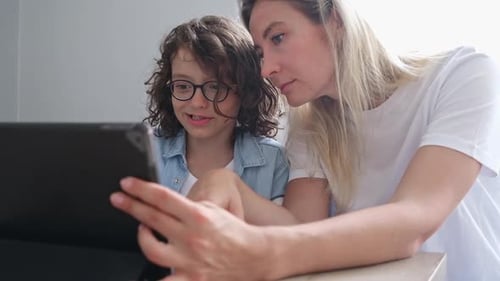 Child and Woman Use Tablet Together Indoors