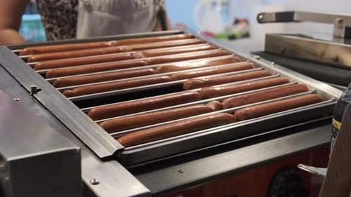 Hotdog Sausages Being Cooked on Grill on at Street Food Festival at Night.