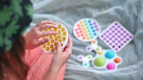 Teen Girl Plays with Antistress Toys Popit and Simple Dimple in the Park on a Summer Day