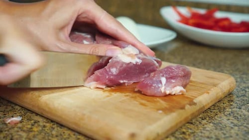 Raw Meat Sliced with Knife on Cutting Board