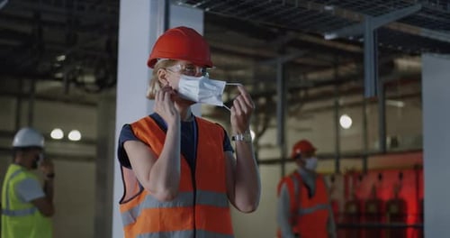 Female Worker Puts on Mask in Industrial Setting