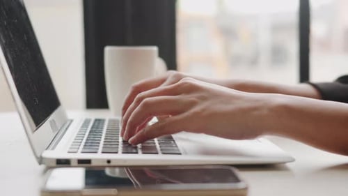 Hands Typing on Laptop Keyboard in Workplace