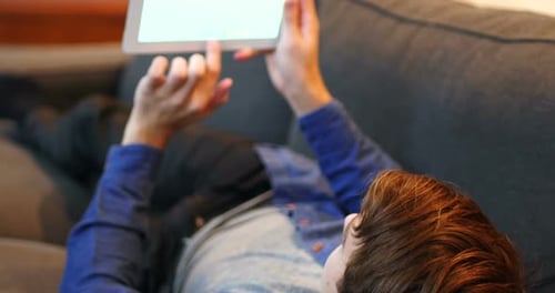 Young Adult Using Tablet While Relaxing on Couch