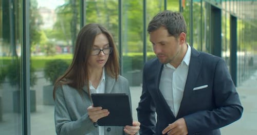 Business People Going To Work with Digital Tablet on Street. Man and Woman Walking Near Office in