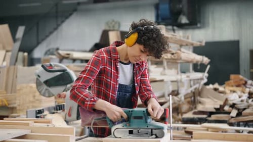 Female Carpenter Working with Wood Using Electric Polishing Machine in Workshop