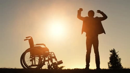 Person Stands Next to Wheelchair at Sunrise