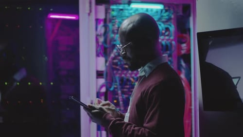 Server Engineer Typing on Tablet in Dark Room