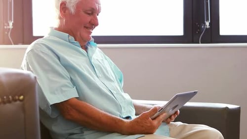 Senior Man Using Tablet Device and Smiling Indoors