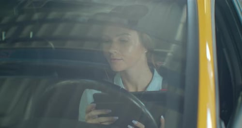 Female Mechanic Sitting in Car Doing Diagnostics on Digital Tablet.
