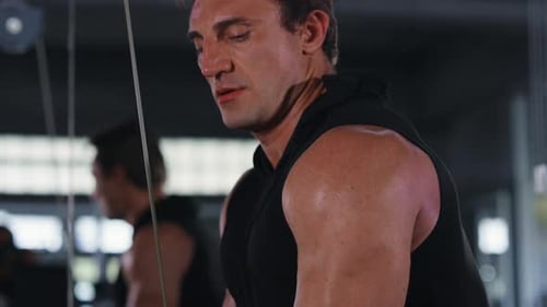 4K Caucasian man bodybuilder pulling weight lifting machine at gym.