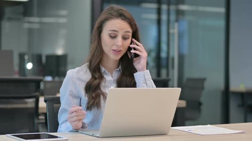 Woman Working at Desk and Talking on Phone