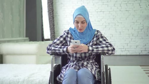 Woman in Wheelchair Using Smartphone in Modern Home