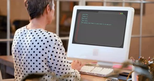 Rückansicht einer weiblichen Führungskraft, die am Schreibtisch am Computer arbeitet