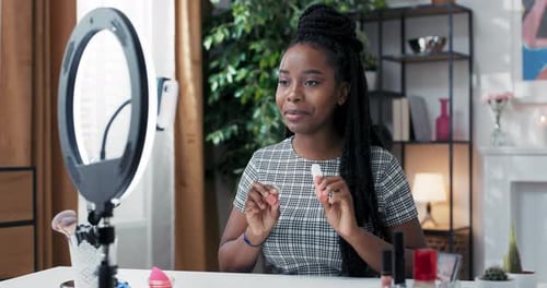 Blogger de belleza femenina filmando tutorial de rutina de maquillaje diario con anillo de luz con teléfono en trípode