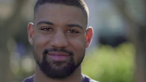 Closeup of Young Male Face in Park Looking at Camera, Smiling