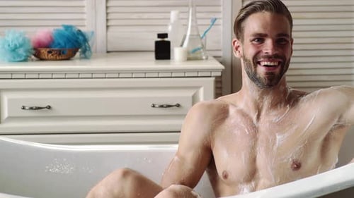 Man Washing in Bathtub with Sponge and Soap