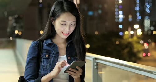 Woman using mobile phone in city at night