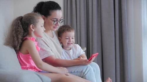 Mother and Children Looking at Smartphone on Couch