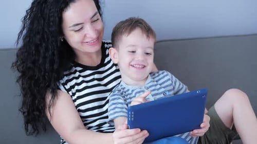 Smiling Woman and Boy Using Tablet on Couch