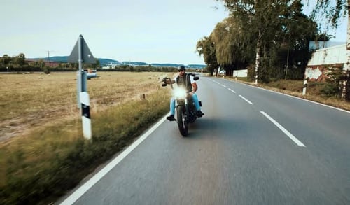 Motorcyclist Rides Down Rural Road on Sunny Day