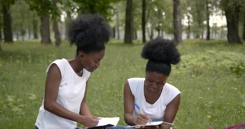 Deux jolies jeunes filles étudiantes assises sur une herbe sur le campus