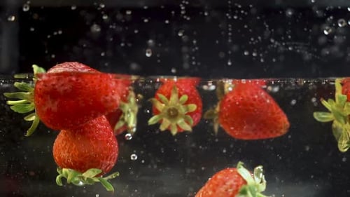Ein paar reife Erdbeeren, die in eine Flüssigkeit geraten