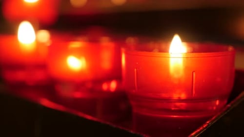 Burning Candles in Red Holders in Dark Setting