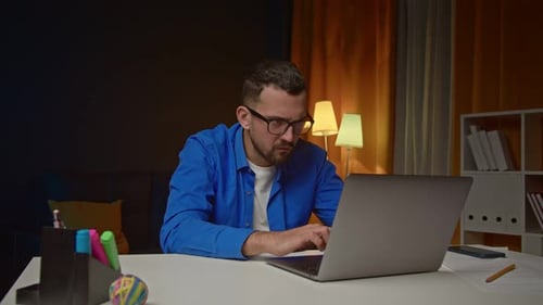 Man working on laptop with a frustrated expression