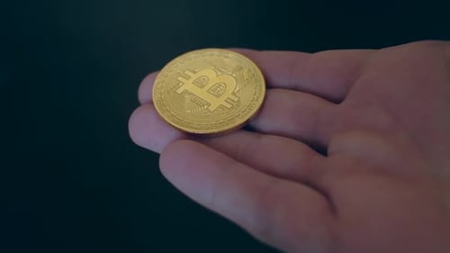 Hand Holding a Single Gold Bitcoin Currency