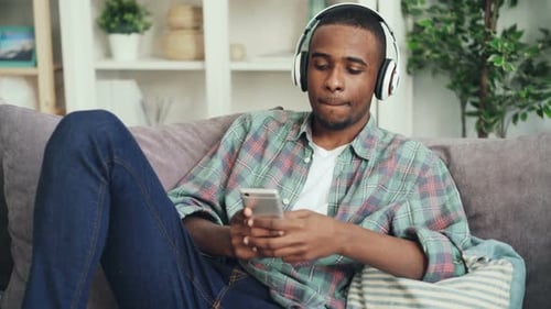 Man Relaxing on Couch with Phone and Headphones