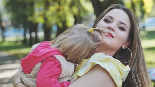A Mother Hugs Her Young Daughter in the Park in the Summer