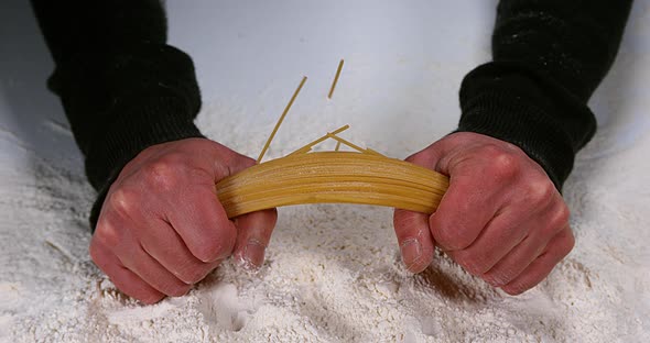 Hands of Man Breaking Spaghetti Pasta against Flour Background, Slow ...