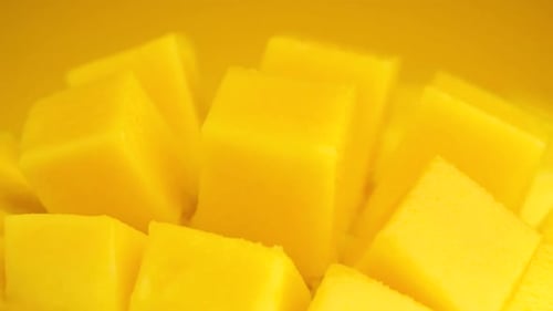 Macro shot Slice mango cubes rotating against Yellow background, Tropical Fruit