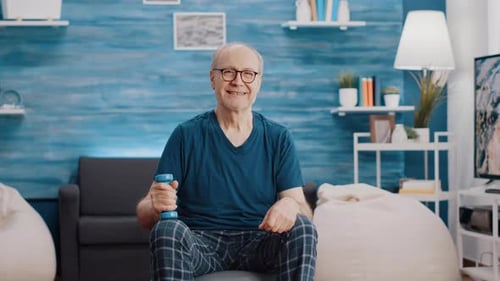Smiling Senior Man Holding Dumbbell in Living Room