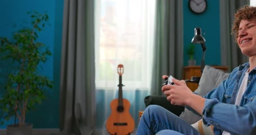 Teenager playing video games on console at home