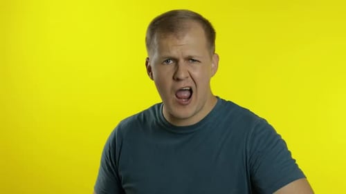 Portrait of Young Caucasian Man Posing in Green T-shirt. Dissatisfied, Picky Guy Looking To Camera