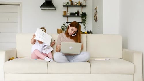 Mother Working From Home Having a Work Video Call Phone Call and Child Playing Nearby