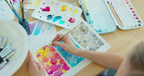 Hand with Brush Painting with Watercolor Abstract Stains.