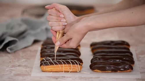 Woman Decorating Chocolate Eclairs with Icing