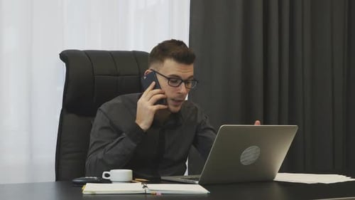 Angry male boss talking on phone and screaming sitting in his modern office. Business concept