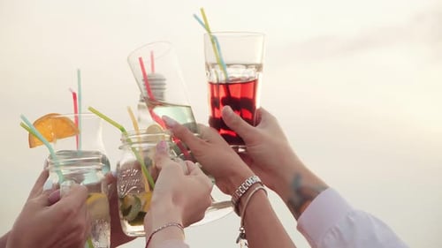 Des mains très levées avec des verres à cocktail lumineux