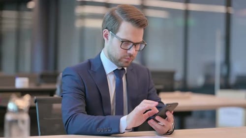 Businessman Browsing Internet on Smartphone in Office