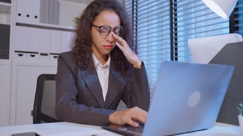 Tired Businesswoman Working Late at Office Desk