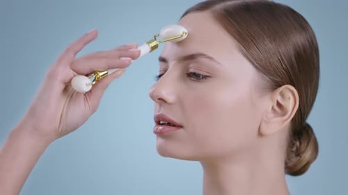 Portrait of Pretty Woman Using Facial Massage Roller for Massaging Nose and Forehead