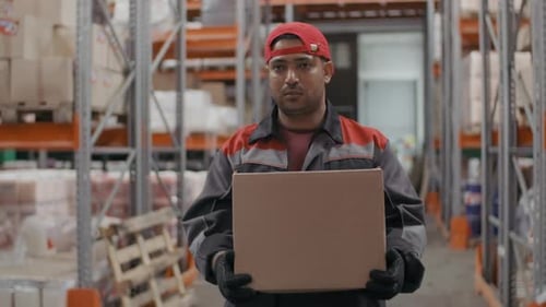 Ernsthafter Lagerarbeiter mit Kartonbox